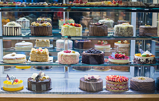 Artisanal bakery hero photograph, aesthetic warm pastel lighting, an elegant bespoke floral buttercream cake, delicate gourmet cupcakes with swirl frosting, rustic marble and linen background, warm tones, sage green botanicals, soft lighting, professional culinary food photography, clean composition